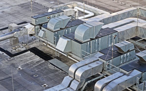 Tetőre telepített légkezelő egységek és légcsatornák egy meglévő épületen.